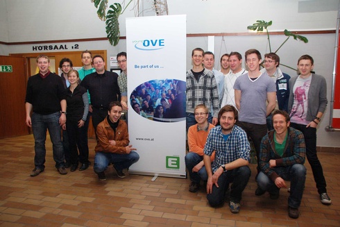 Gruppe von Menschen vor einem Banner mit dem Logo von OVE.