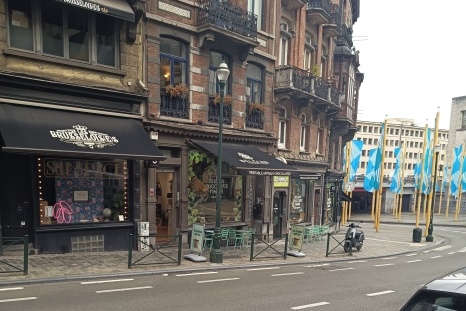 Straßenszene mit Cafés und bunten Flaggen in einer städtischen Umgebung.