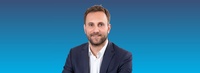 Porträt eines Mannes in Anzug mit lächelndem Gesicht.