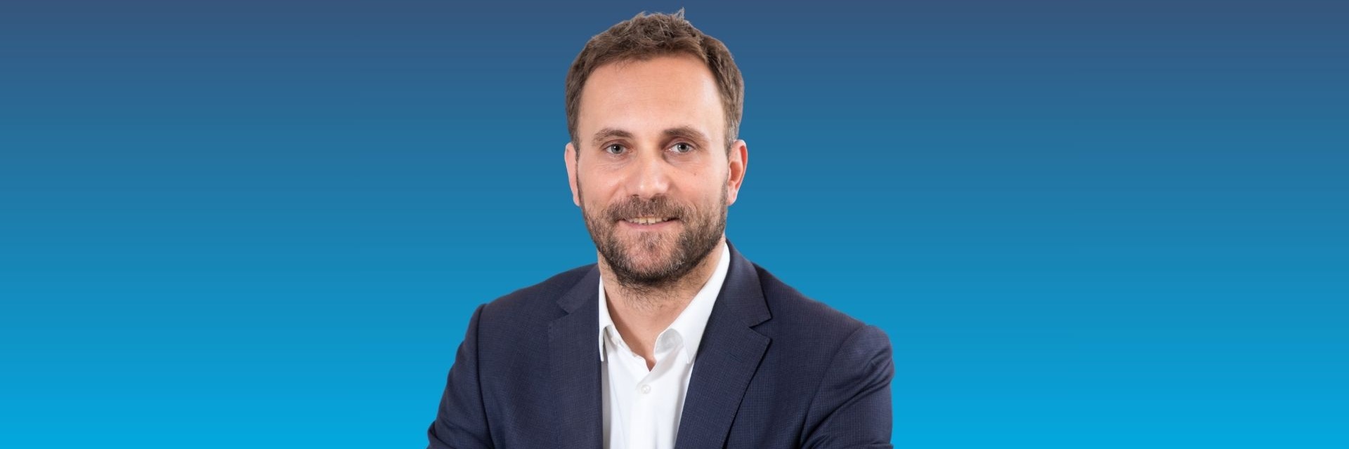Porträt eines Mannes in Anzug mit lächelndem Gesicht.