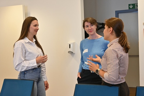 Drei Frauen führen ein Gespräch in einem freundlichen, modernen Raum.