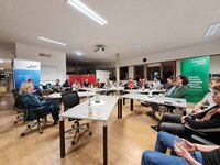 Eine Gruppe von Menschen sitzt in einem Besprechungsraum und diskutiert.