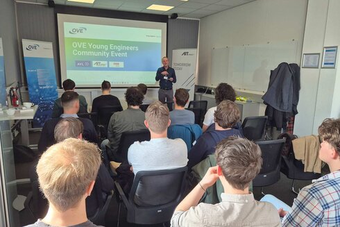 Ein Dozent spricht vor einer Gruppe junger Ingenieure bei einem Event.