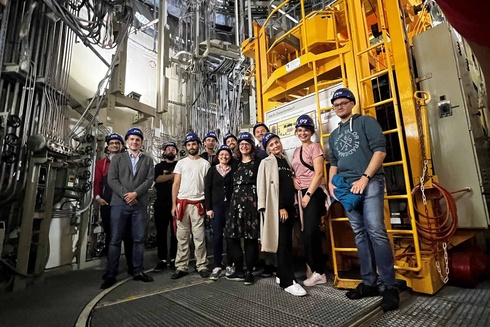 Gruppe von Menschen vor einer großen, technischen Anlage in einem Industrieumfeld.