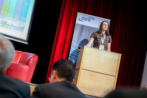 Eine Frau spricht an einem Podium während einer Präsentation.