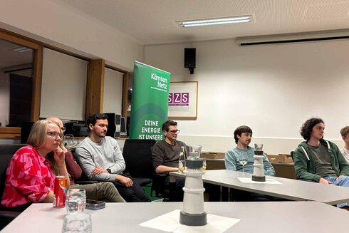 Eine Gruppe von Menschen in einem Raum, die einem Vortrag zuhören.