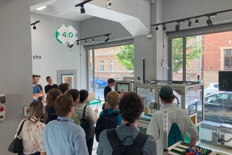 Gruppe von Menschen sieht sich eine Ausstellung in einem Raum an.