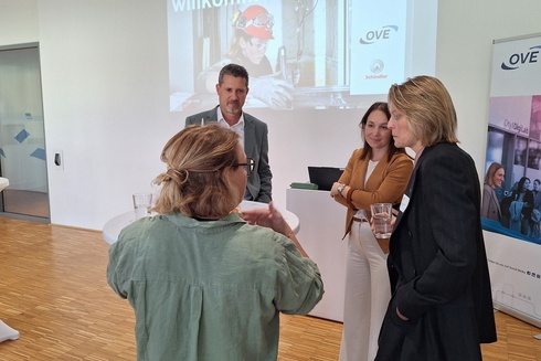 Vier Personen unterhalten sich bei einer Veranstaltung in einem modernen Raum.