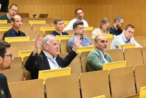 Eine Gruppe von Menschen in einem Seminarraum, einige hören zu, andere diskutieren.