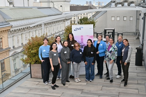 Eine Gruppe von Frauen posiert auf einer Dachterrasse vor einem OVE-Stand.