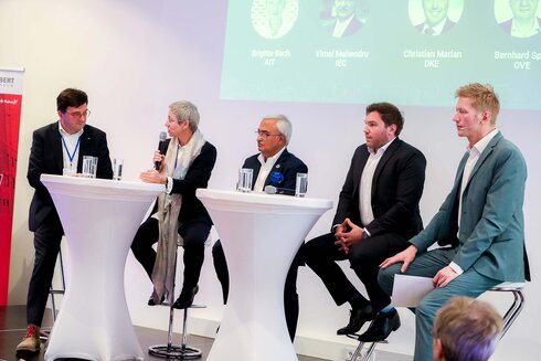 Podiumsdiskussion mit fünf Teilnehmern an Stehtischen.