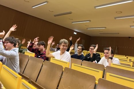 Eine Gruppe von Schülern hebt die Hände in einem Klassenraum.