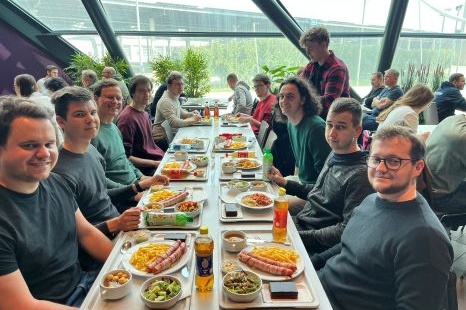 Gruppe von Personen an einem Tisch mit verschiedenen Gerichten und Getränken.