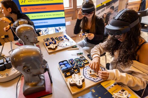 Zwei Frauen arbeiten an Technikprojekten mit VR-Brillen und Elektronik-Kits.