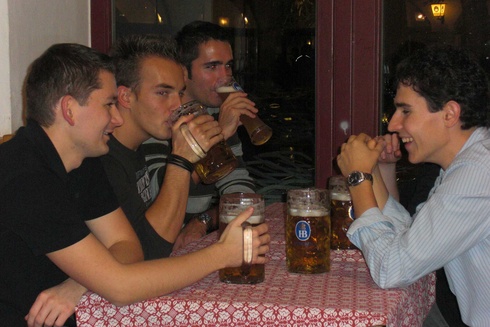 Vier Männer sitzen an einem Tisch und trinken Bier.