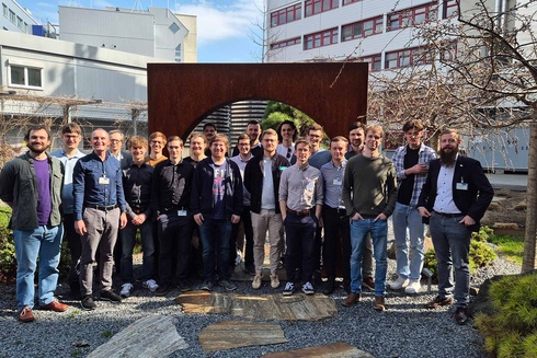 Gruppe von 20 Personen posiert lächelnd vor einer Gartenarchitektur.