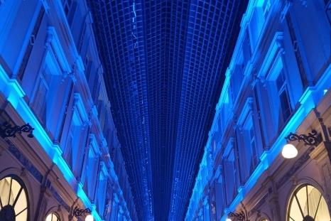 Blick in eine beleuchtete Passage mit blauen Wänden und einem Gitterdach.