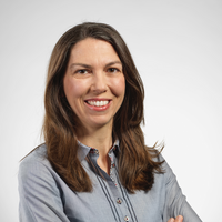 Eine Frau mit lächelndem Gesicht, die ihre Arme vor der Brust verschränkt.