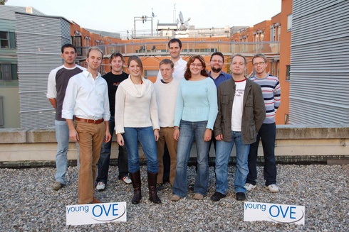 Gruppe von zwölf Personen, die zusammen draußen stehen, mit „young OVE“-Schilden.