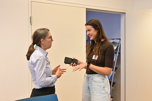 Zwei Frauen unterhalten sich, eine hält ein Smartphone in der Hand.