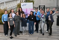 Gruppe von Frauen posiert fröhlich vor einem Banner auf einer Dachterrasse.