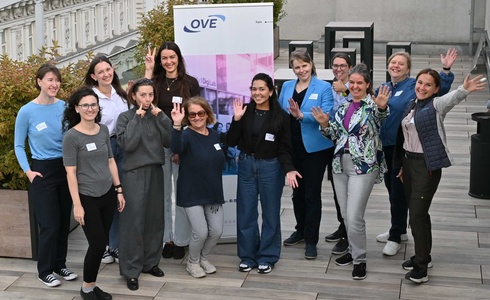 Gruppe von Frauen posiert fröhlich vor einem Banner auf einer Dachterrasse.