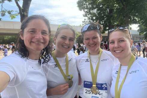 Vier Frauen mit Medaillen lächeln in die Kamera nach einem Wettlauf.
