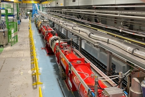 Ein langer technischer Tunnel mit roten Maschinen und Rohren zur Forschung.
