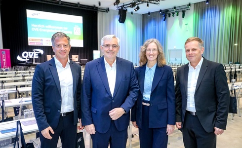 Vier Personen stehen zusammen bei einer Veranstaltung, lächeln und sehen in die Kamera.