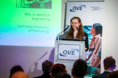 Eine junge Frau spricht an einem Rednerpult über Elektrotechnik.