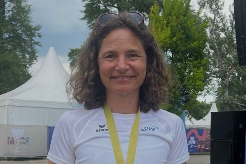 Eine Sportlerin hält stolz ihre Medaille in der Hand.