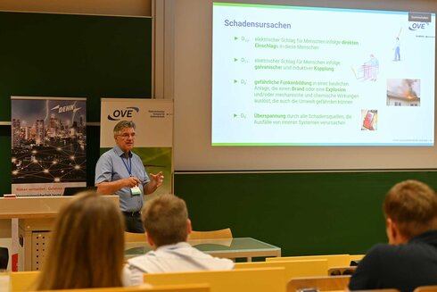 Ein Referent erklärt Schadensursachen vor einem Publikum in einem Seminarraum.