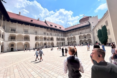 Innenhof eines historischen Gebäudes mit vielen Besuchern und blauem Himmel.