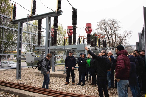Gruppe von Menschen bei einer Schulung an einer elektrischen Anlage.
