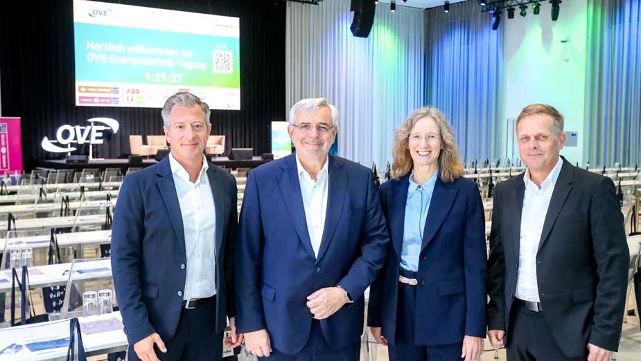 Gruppenbild von vier Personen in formeller Kleidung auf einer Konferenz.