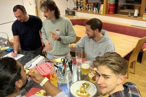 Freunde genießen gemeinsam Essen und Getränke an einem Tisch.