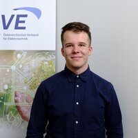 Junger Mann steht vor einem Banner des Österreichischen Verbands für Elektrotechnik.