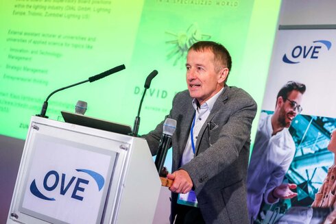 Ein Mann steht an einem Rednerpult und hält einen Vortrag über Beleuchtung.