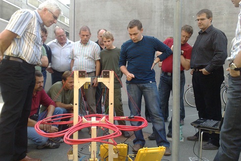 Gruppendiskussion von Männern und Jungen über ein technisches Gerät im Freien.