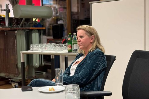 Frau in einem blauen Anzug sitzt nachdenklich an einem Tisch.