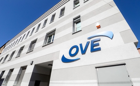 Gebäude mit grauer Fassade und dem Logo „OVE“ an der Wand.