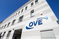 Gebäude mit grauer Fassade und dem Logo „OVE“ an der Wand.