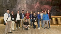 Gruppe von 15 Personen auf einer Holzplattform in einer Bergwerk-Umgebung.