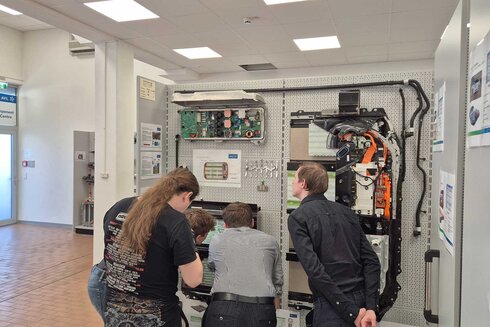 Vierte Personen untersuchen ein technisches Gerät an einer Wand.