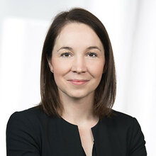 Porträt einer Frau mit lächelndem Gesicht, die in schwarz gekleidet ist.
