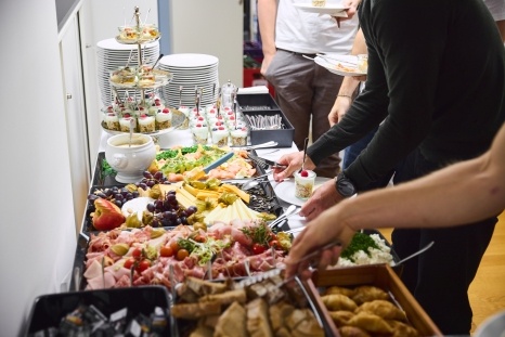 Ein Buffet mit verschiedenen Speisen, darunter Fleisch, Käse, Obst und Desserts.