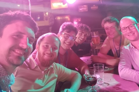 Sechsköpfige Gruppe von Freunden bei einem geselligen Treffen in einer Bar.