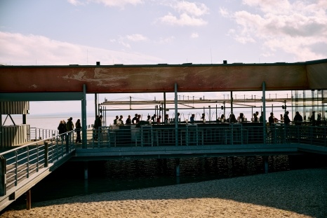 Ein Restaurant mit vielen Menschen, die auf einer Terrasse am Wasser sitzen.