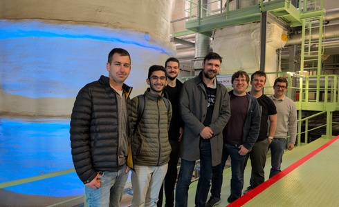 Eine Gruppe von sieben Personen steht in einer industriellen Umgebung.