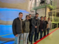Eine Gruppe von sieben Personen steht in einer industriellen Umgebung.